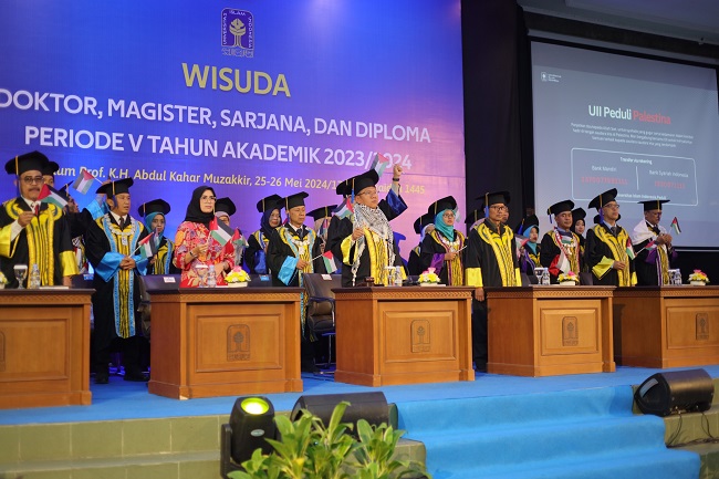 Rektor, pimpinan dan wisudawan UII mengibarkan bendera Palestina pada wisuda di Auditorium Abdul Kahar Mudzakkir, Sabtu (25/4/2024). (foto : istimewa)