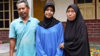 Mar’atul Hofizah diapit kedua orang tuanya di depan rumahnya, Dusun Gubuk Timuk, Desa Korleko, Kecamatan Labuhan Haji, Kabupaten Lombok Timur, Nusa Tenggara Barat. (foto : screenshotugmacid)