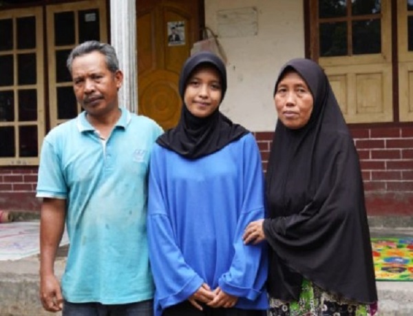 Mar’atul Hofizah diapit kedua orang tuanya di depan rumahnya, Dusun Gubuk Timuk, Desa Korleko, Kecamatan Labuhan Haji, Kabupaten Lombok Timur, Nusa Tenggara Barat. (foto : screenshotugmacid)